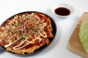 Okonomiyaki in the skillet on the table