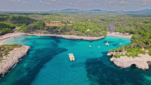 Cala Mondrag&oacute; and Platja de s'Amarador beaches with white sand and blue waters. People relaxing on holiday by the beach with boats and vessels floating by the coast in Majorca, Balearic Islands, Spain