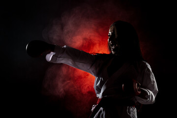 beautiful girl exercising karate punch against red fog background..