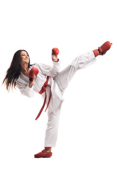 girl exercising karate leg kick wearing kimono and red gloves against white background..