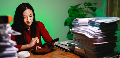 Banner size of Businesswoman make the business reports by digital tablet during overtime at home