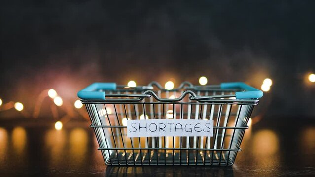 economy after covid, shortages text on empty shopping basket  on dark background with lights