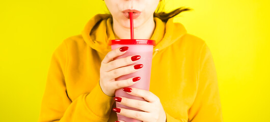 Body part of woman with red manicure holding large cup. Crop unrecognizable person drinking through...