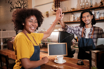 Two cafe business startup partners and friends, African American female, and Thai male baristas...