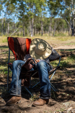 A teenage girl having a nap lounging in camp chair, with hat covering face.