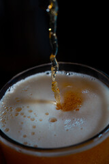 Close-up of beer streaming into pint with foam head