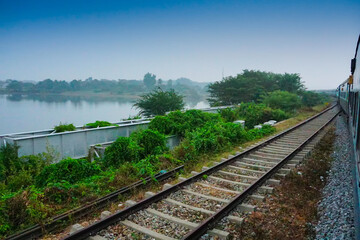 Fototapeta premium A train passing beside backwaters of Kerala, India - The Kerala backwaters are a network of brackish lagoons and lakes lying parallel to the Arabian Sea coast southern India. Blue sky background.