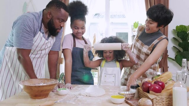 Happy African American kids and family preparing flour to make bread in kitchen at home.