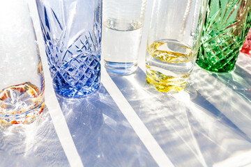 Row of colourful glasses with sunlight shining through them - light and shadows