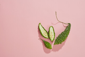 Top view of bittermelon in petri dish and green leaf with blank space pink background