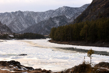 Frozen bed of a beautiful river flowing through a valley with snow-capped mountains.