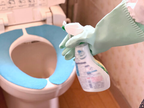 トイレ掃除をするビニール手袋をして洗剤を持つ手