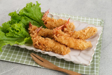 Fried breaded shrimp with vegetable on plate, served with chilli sauce
