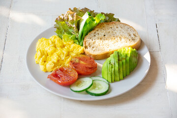 breakfast scrambled eggs, avocado, toast on a white background in natural light
