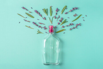 Glass bottle of perfume and leaves and flowers on a green blue background. Concept of a lavender...