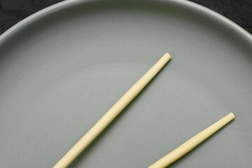 grey plate and chopsticks on a black background