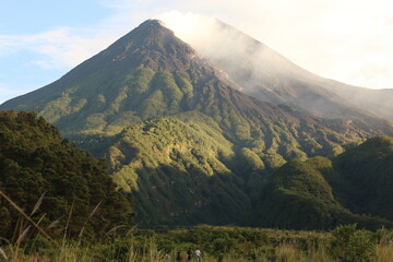 Fototapeta premium Morning light on mount Merapi Indonesia. Gunung Merapi or Mount Merapi, is an active stratovolcano located on the border between the province of Central Java and the Special Region of Yogyakarta.