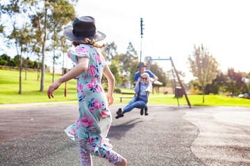 Child, teen and young adult siblings playing together on flying fox swing at playground