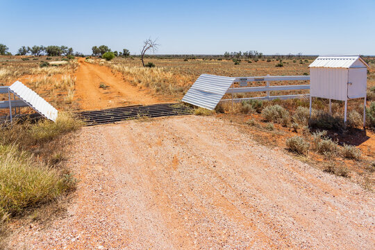 A mailbox and cattle grate over a dirt track in an outback landscape