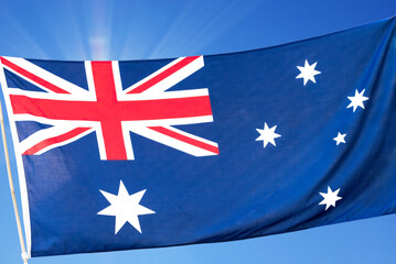 Australian flag blows in the wind against blue sky background