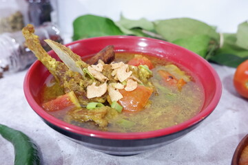 shurpa - oriental soup with vegetables and lamb served in a red bowl topped with fried garlic. 