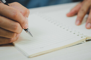 Fototapeta premium person holding a pen writing notes at a notebook.
