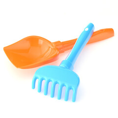 A set of children's toys for playing in the sandbox. Colored rake and shovel made of plastic, isolated on a white background, close-up. Early child development, children's leisure concept