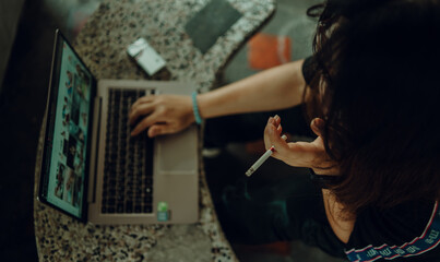 woman in black shirt working with laptop and stressing about work hand smoking cigarette unhealthy lifestyle concept