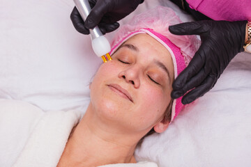 beautiful adult woman. doing facial treatment with plasma jet in beauty clinic.