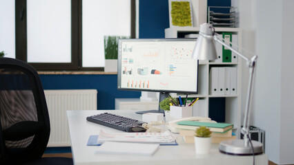 Computer screen with sales statistics on diagram at desk in empty startup office. No people in professional workplace with monitor showing financial data charts for business growth.