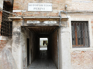 street of Venice in Italy and the text that means Under the Porch called PERINI and the indication...