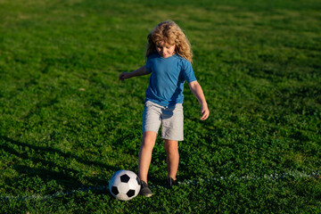 Soccer child play football. Kid kicking a football ball on a grass. Sports kid during soccer...