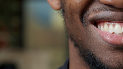 Macro shot of young man moving his lips and smiling, showing half of face on camera. Happy...