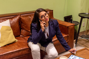 Portrait of young white woman in a busy modern workplace working and  holding phone or tablet in a...
