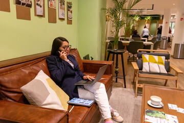 Portrait of young white woman in a busy modern workplace working and  holding phone or tablet in a...