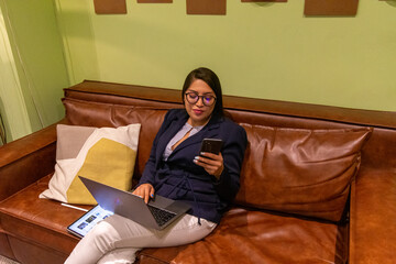 Portrait of young white woman in a busy modern workplace working and  holding phone or tablet in a...