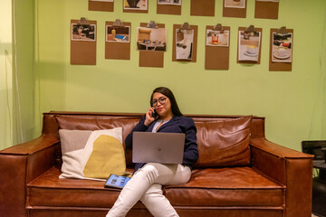 Portrait of young white woman in a busy modern workplace working and  holding phone or tablet in a...