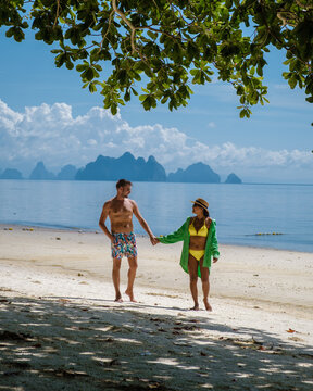 couple of men and woman on the beach of the tropical Island Naka Island near Phuket Thailand, woman at a swing on the beach, and man walking on a tropical beach