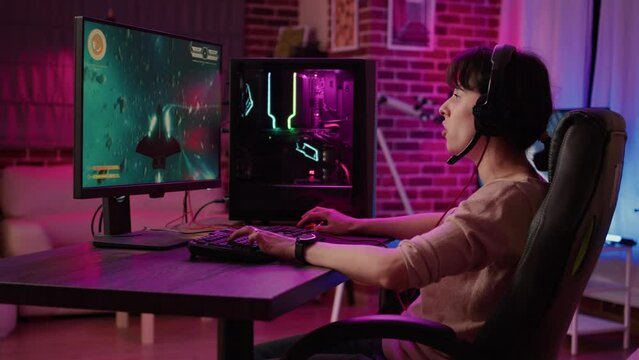 Woman relaxing and streaming on internet fast paced space shooter simulation gameplay while talking using headset. Gamer girl playing rpg action game on professional pc setup in living room.