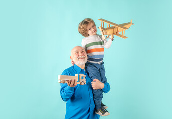 Young grandson and old grandfather piggyback with toy plane and wooden truck. Men generation granddad and grandchild.