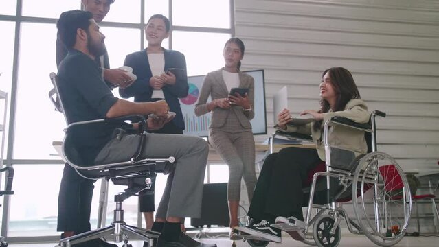 A disabled company employee is able to work happily with colleagues in the office.