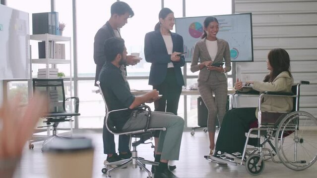 A disabled company employee is able to work happily with colleagues in the office.
