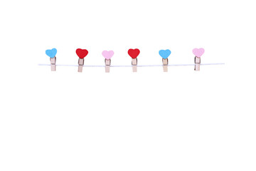 Six wooden clothes pins in heart shape patterns hanging on white rope isolated on white background , clipping path