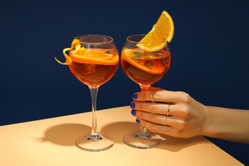 Concept of summer alcohol drink, female hand holds Aperol Spritz