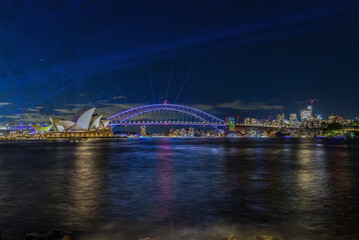 Colourful Light show at night on Sydney Harbour NSW Australia. The bridge illuminated with lasers and neon coloured lights. Sydney laser light show