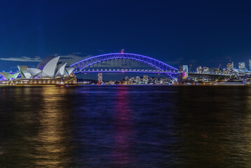 Naklejka na ściany i meble Colourful Light show at night on Sydney Harbour NSW Australia. The bridge illuminated with lasers and neon coloured lights. Sydney laser light show