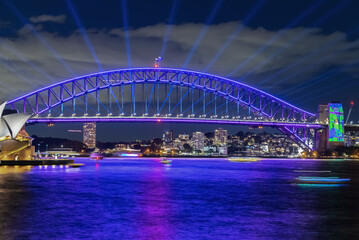 Fototapeta na wymiar Colourful Light show at night on Sydney Harbour NSW Australia. The bridge illuminated with lasers and neon coloured lights. Sydney laser light show