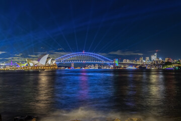 Colourful Light show at night on Sydney Harbour NSW Australia. The bridge illuminated with lasers and neon coloured lights. Sydney laser light show