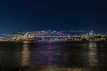Colourful Light show at night on Sydney Harbour NSW Australia. The bridge illuminated with lasers and neon coloured lights. Sydney laser light show