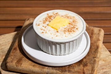 Close up of Risengrod bowl  with butter and cinnamon on wooden table.